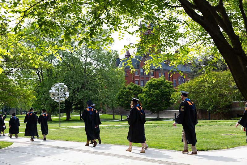 Students walking on campus in their cap and gown